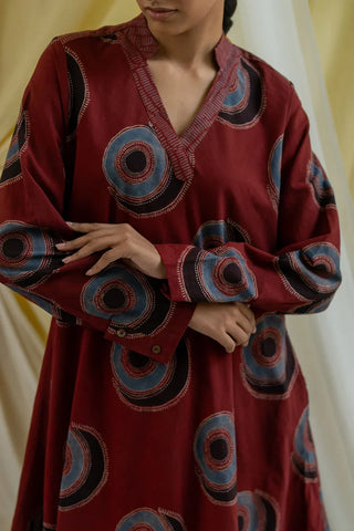 Close-up of V neckline, printed collar band and button cuffs on burgundy block print tunic