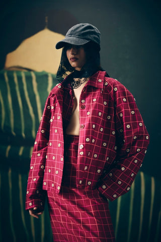 Chic maroon checked outfit featuring a skirt, embroidered bustier, and matching shirt. A stylish combination of classic patterns and modern tailoring for elevated everyday or event wear.