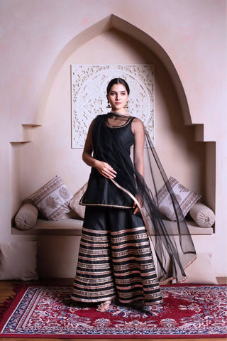Model wearing Ghazal black cotton silk gota patti sharara set, women’s designer ethnic outfit styled for festive occasions, weddings and traditional celebrations.
