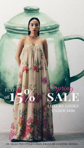 A woman wearing a cream floral Jumpuit stands to pose with promotional text on the left reading 'Spring SALE' and 'up to 15% off'. Luxury Looks Under $400. shop New In Edit.