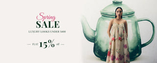 A woman wearing a cream floral Jumpuit stands to pose with promotional text on the left reading 'Spring SALE' and 'up to 15% off'. Luxury Looks Under $400. shop New Edit.