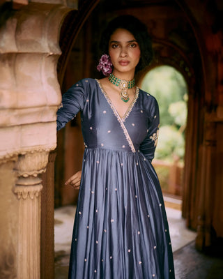 Woman in a dark blue anarkali embroidered dress standing in an architectural setting. A desi vibe for any girl who wants to celebrate her roots.