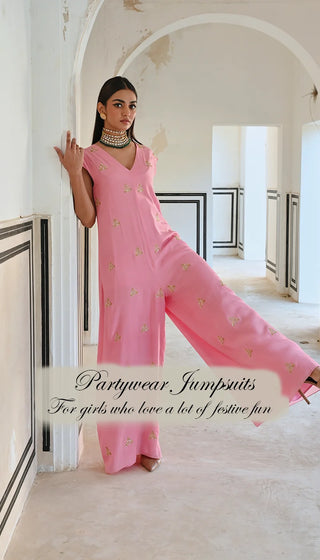 A model in pink jumpsuit posing in playful vibe in heavy jewellery. A Designer Fusion Jumpsuits perfect for Festive Occasion Wear.