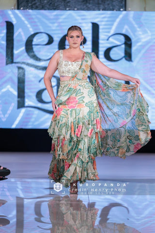 A rich green and ivory floral printed pre-draped chiffon ruffle saree featuring elegant prints and lace detailing . It is paired beautifully hand-embroidered blouse. Perfect for wedding, partes, events.