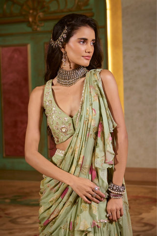Close-up of the tiered lace detailing on the rich green chiffon saree and the delicate hand embroidery on the V-neck blouse.