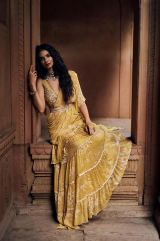 A yellow vintage romantic floral printed chiffon pre–draped saree with hand–embroidered lace detailing, paired with a matching print intricately hand–embroidered deep neck blouse