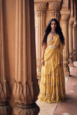 Elegant vintage-style pre-draped yellow chiffon saree featuring soft floral prints and intricate hand-embroidered lace, paired with a  V-neck blouse. Designed by Paulmi and Harsh.