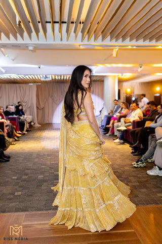 Model showcasing back look of pre-draped yellow chiffon saree featuring soft floral prints and intricate hand-embroidered blouse at Australian Fashion Show Grandeur Runway.