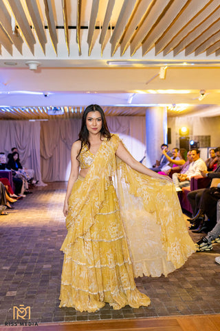 Model in elegant vintage-style pre-draped chiffon saree featuring soft floral prints and intricate hand-embroidered lace, paired with deep neck blouse at Australian Fashion Show Grandeur Runway.