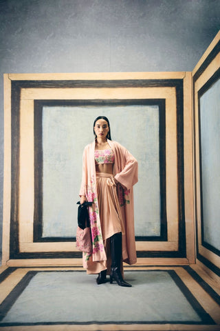A baby pink embroidered jacket set with an asymmetric skirt and tie-up belt. It is paired with a fully embroidered bustier, adding a contemporary layer and effortless sophistication. Creating a refined designer ensemble for elegant parties, birthday brunches, and evening occasions. 