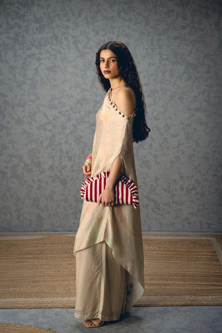 Side profile of the ivory satin ensemble showcasing fluid drape and relaxed one-shoulder silhouette.