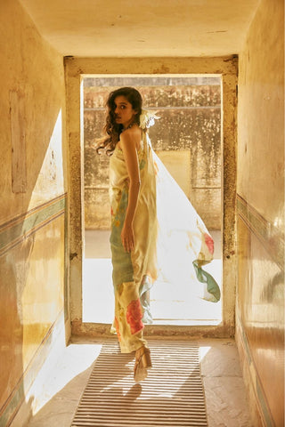 Women in Indo Western Ivory Habutai Floral Printed Chic Statement One-Shoulder Tunic Set with straight cut Trouser posing for photo shoot near door. It is a perfect outfit for Resort, Casual wear, Party Dress collection.