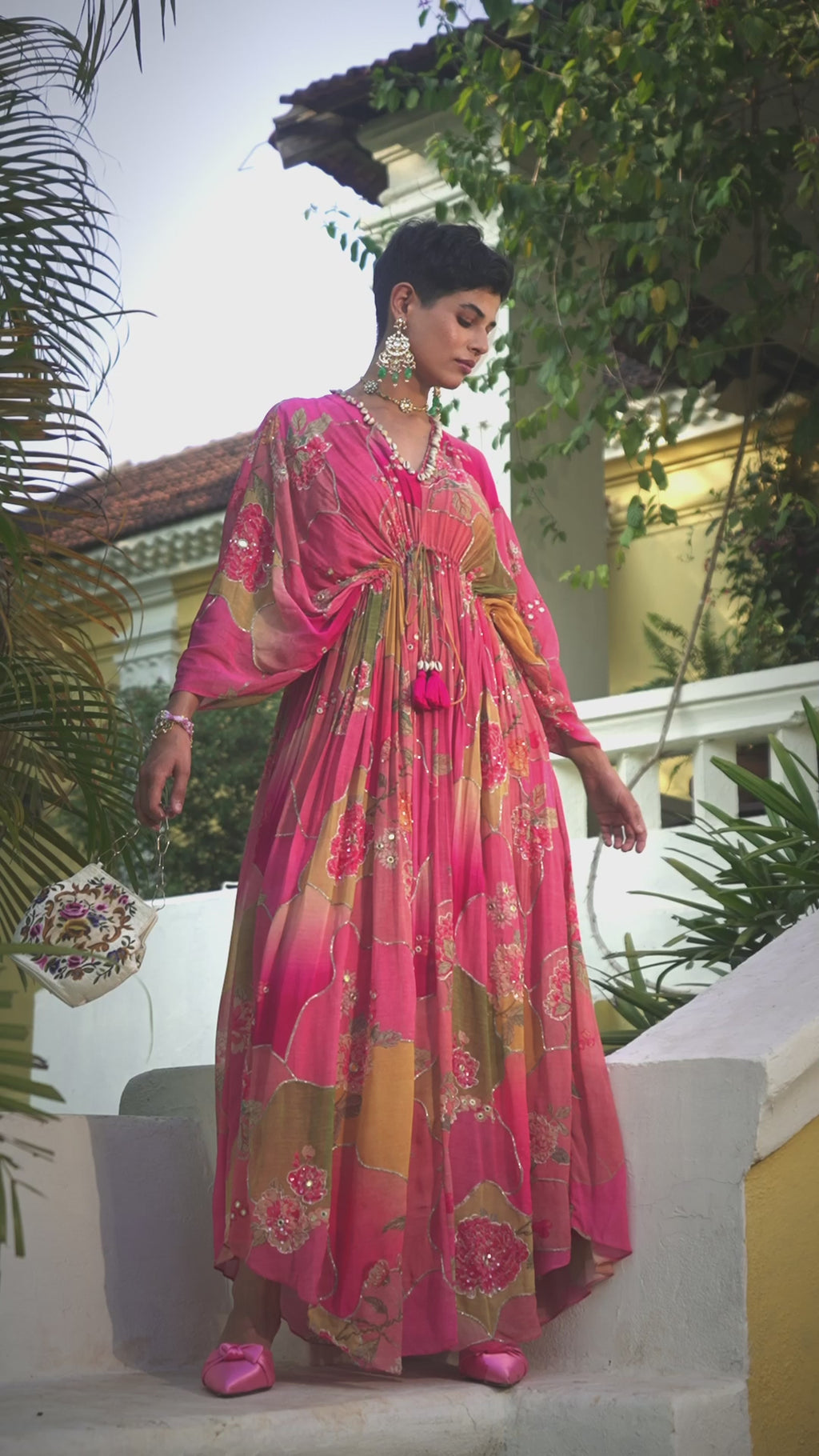 Model posing in bohemian multicolored kaftan suit dress designed by Paulmi and Harsh. The one-size-fits-all silhoutte featuring mirror, sequins, cutdana and zari, V-cut neck. A perfect dress for festivities, parties, cultural events -statement women's ethnic wear.
