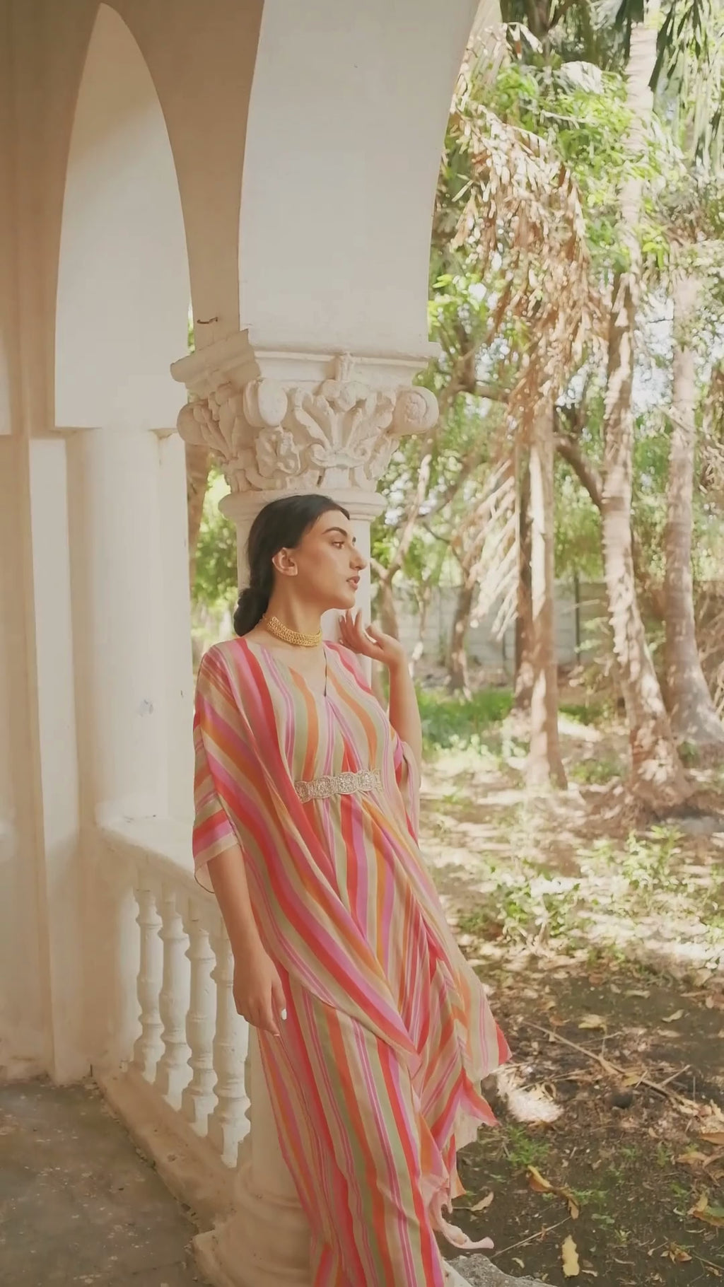 Model in multi–colored striped set of an asymmetric kaftan and skirt paired with a square cut dana belt designed by Paulmi and Harsh. Perfect for costal summer wear, resort and gatherings.