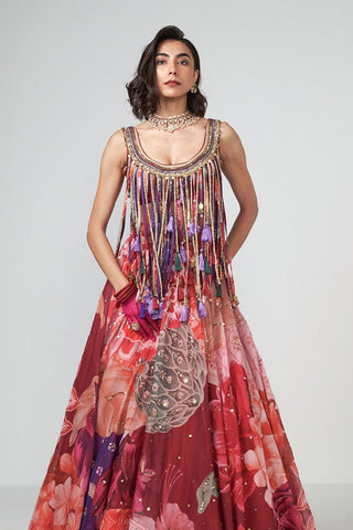 Contemporary cherry lehenga ensemble featuring subtle embellishments, intricate trim detailing, and statement tassel accents for modern bridal and festive glamour.