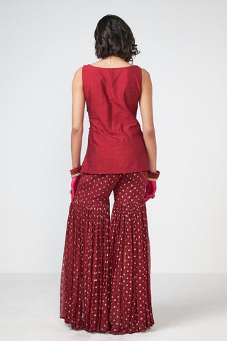 Back look of cola-colored sharara ensemble with handcrafted applique fringe detailing on luxurious dupion and georgette fabric for wedding and festive styling.