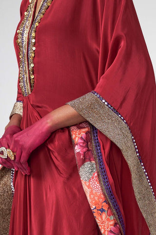 Detailed close-up of delicate hand embroidery and crystal hanging embellishments on rich cherry crepe fabric.