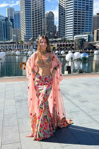 Multicolored lehenga set featuring vibrant prints, embroidered trims, embellished cape, and festive statement silhouette.