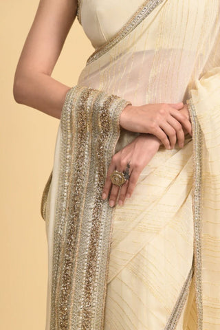 Designer ivory saree, Georgette & Chanderi Silk fabric, Linear trim golden embroidery on the border of the saree.