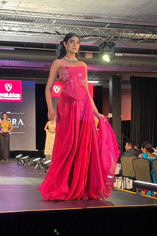Model in fuchsia pink crepe corset lehenga set with handcrafted patchwork detailing and fit-and-flare silhouette by Rishi and Vibhuti, posing at fashion show runway in Australia.