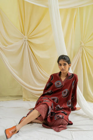 Model seated wearing burgundy hand block printed cotton tunic with circle motifs and matching culottes