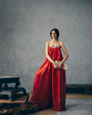 Woman in Red floral organza silk jumpsuit with a flowy silhouette, perfect for party wear, formal events, resort looks, vacation styling, holiday outfits, soirées, and wedding receptions. Designed by Paulmi and Harsh and Ease. Shop this elegant statement jumpsuit online.